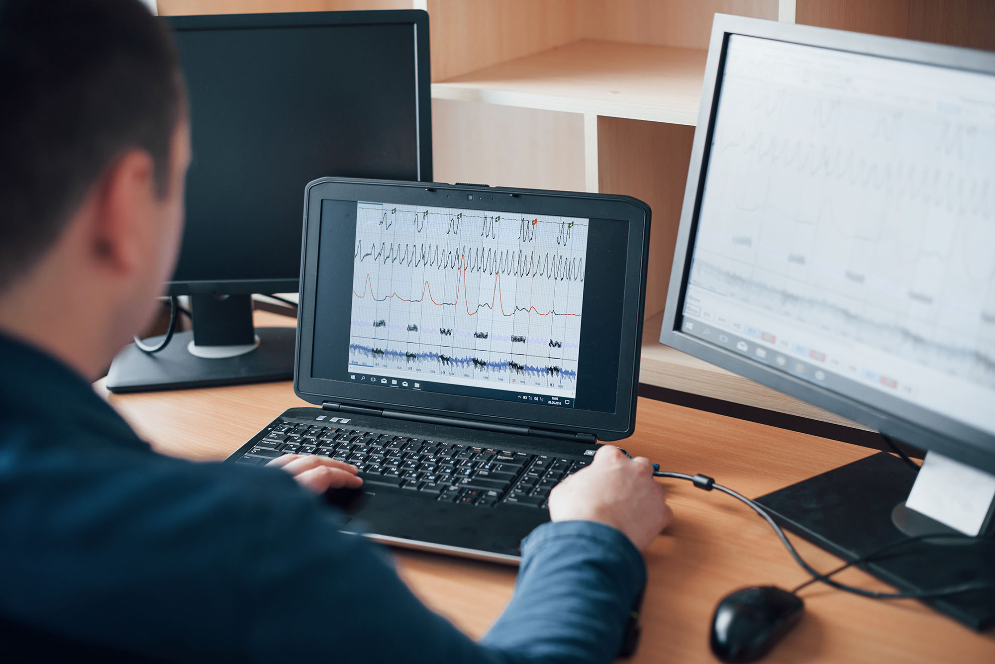 Analizying information. Polygraph examiner works in the office with his lie detector’s equipment Analizying information. Polygraph examiner works in the office with his lie detector's equipment